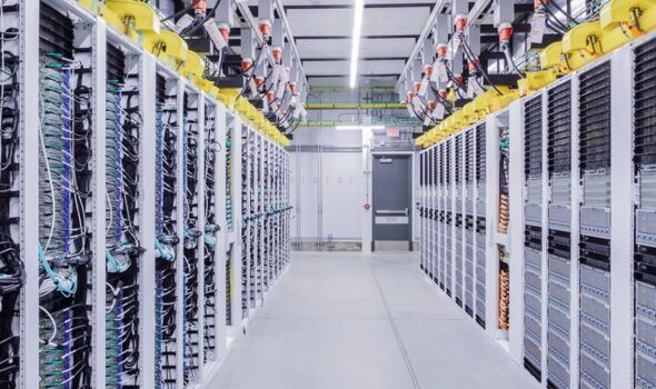 Racks of servers line either side of an aisle inside a data center.