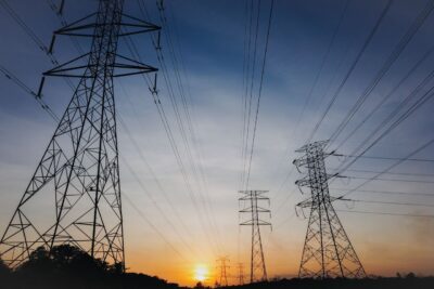 Silhouette of transmission towers against a vibrant sunset sky, showcasing modern infrastructure.
