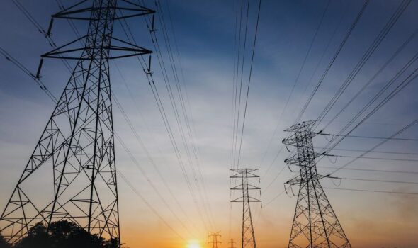 Silhouette of transmission towers against a vibrant sunset sky, showcasing modern infrastructure.
